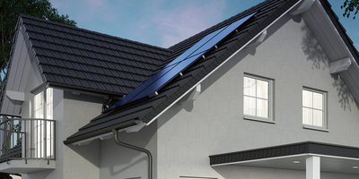 Ein modernes Haus mit einem schrägen Dach, das mit Solarpanelen ausgestattet ist, unter einem klaren Himmel.